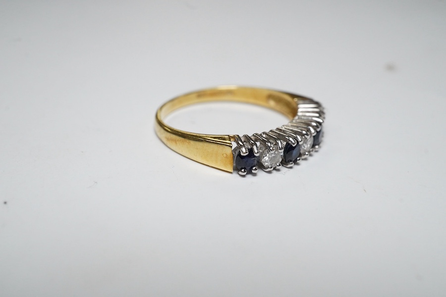 A modern 18ct gold, four stone sapphire and three stone diamond set half hoop ring, size L/M, gross weight 2.4 grams. Condition - fair to good